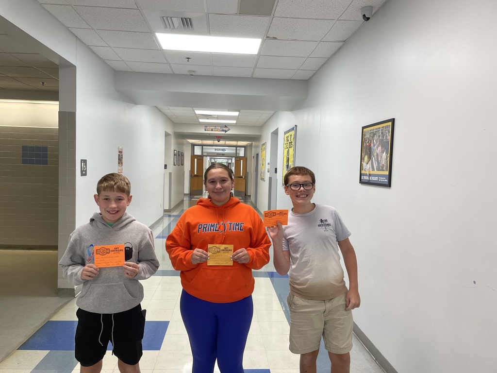 Three students holding orange cards