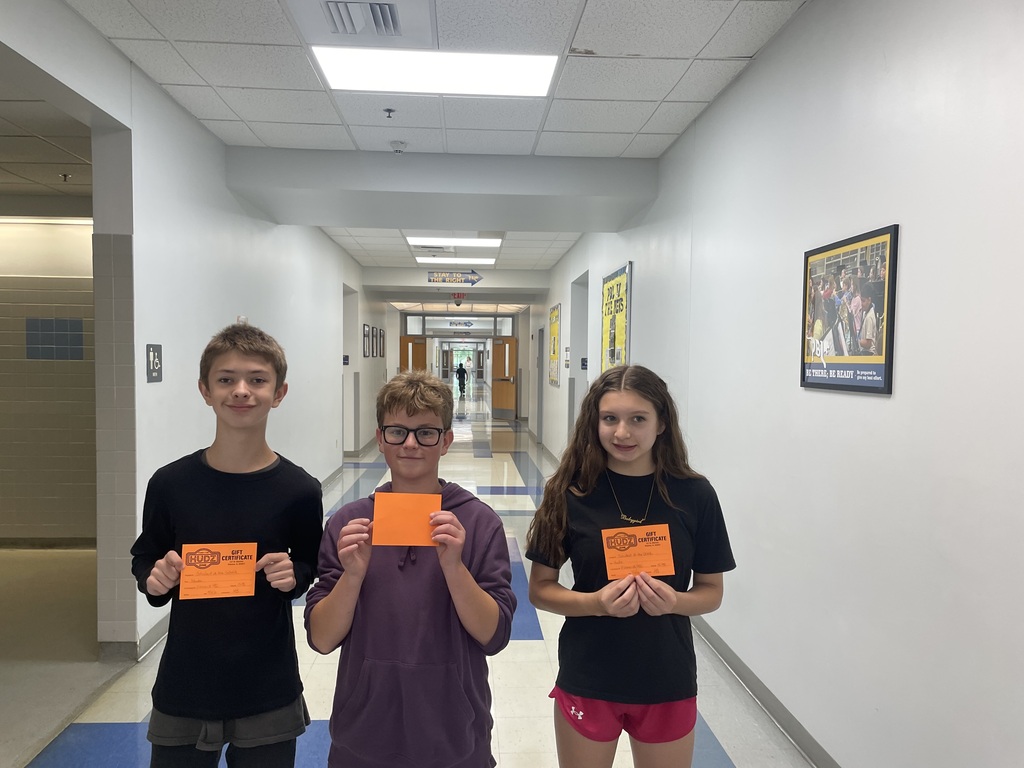 Three students holding orange cards
