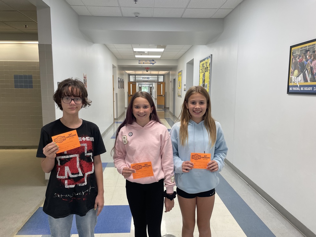 Three students standing holding orange cards