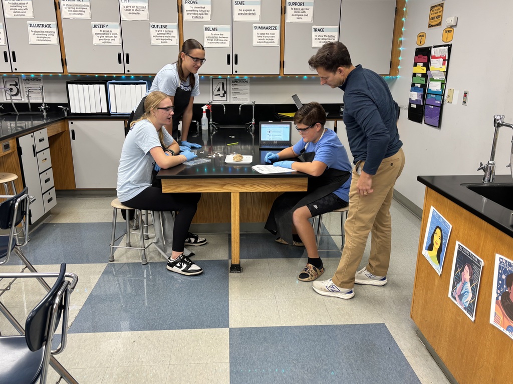 Three students around a table looking at an object