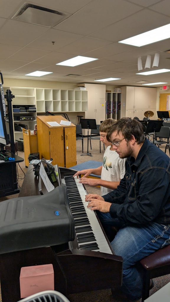 Two boys sitting at a piano playing music
