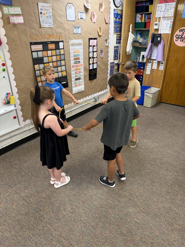 4 students building a shape with a rope