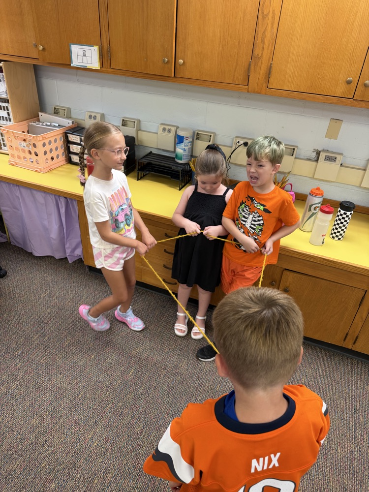 4 students building a shape with a rope