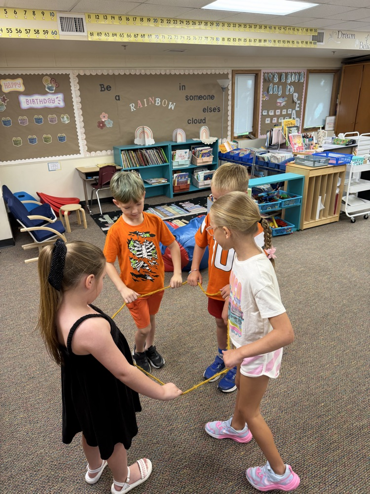 4 students building a shape with a rope