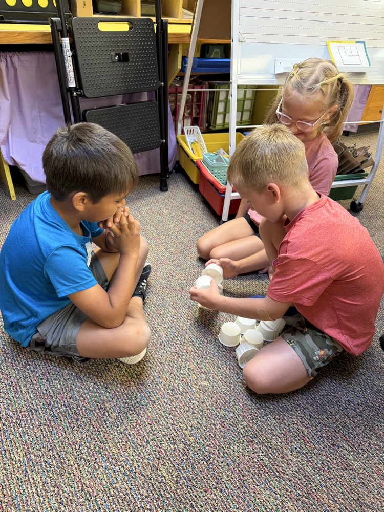 3 students building a cup tower