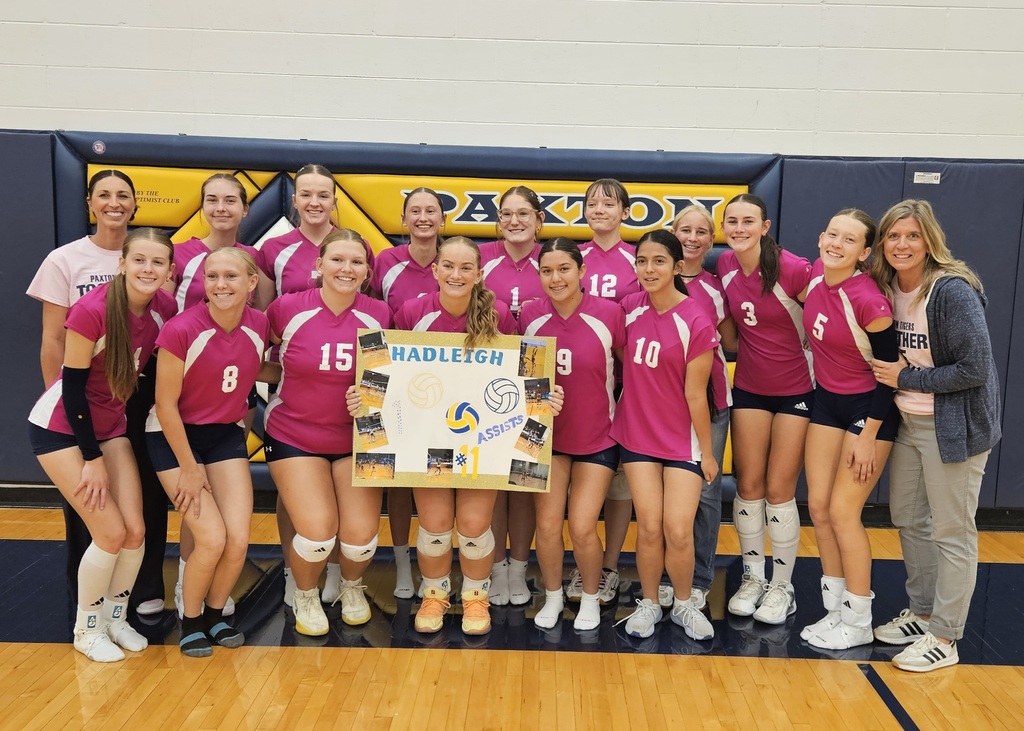 Hadleigh and her teammates smiling holding up a sign for her 1000 career assists