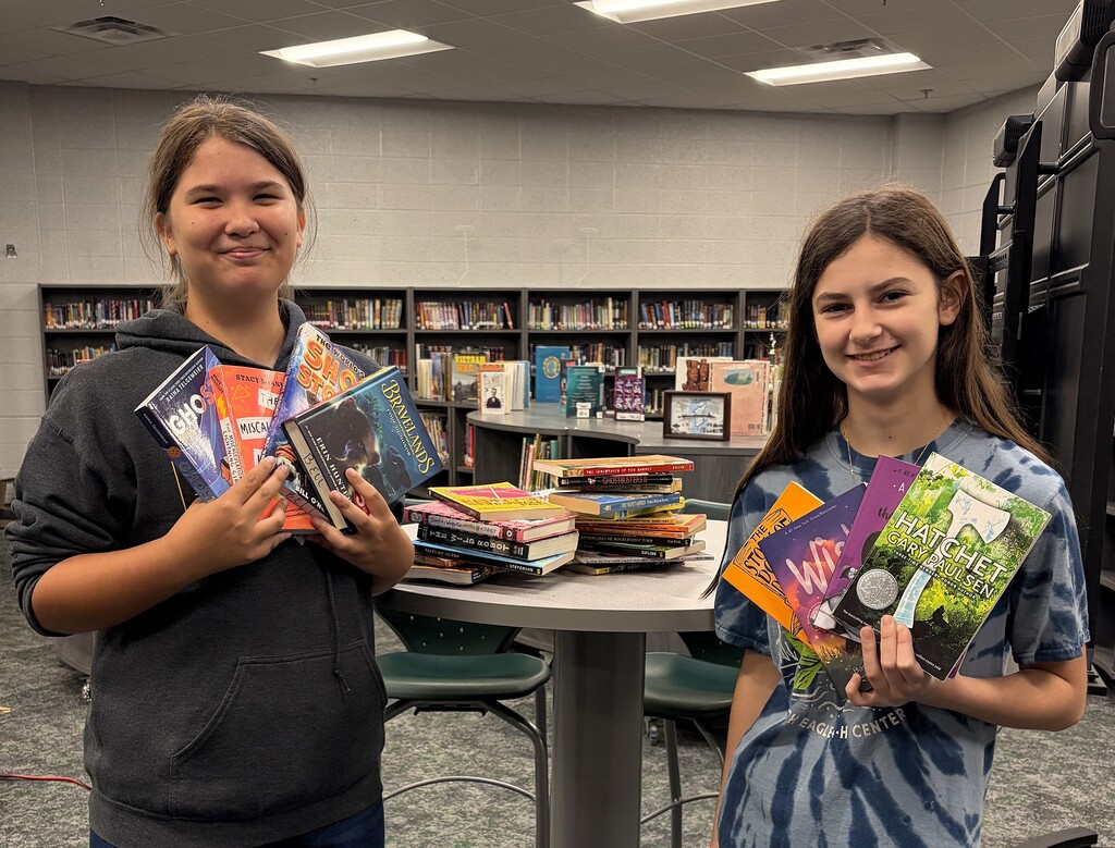 Karabelle and Reagan hold several donated books in the Aerie. 