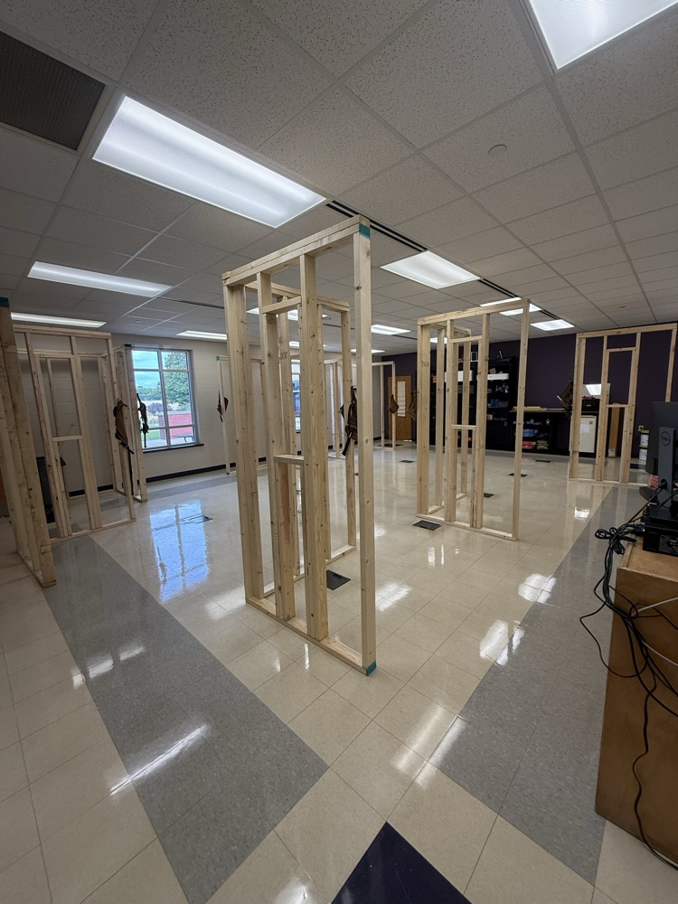 Several full-size wooden wall frames with small window openings stand throughout the Basic Home Ownership classroom. 