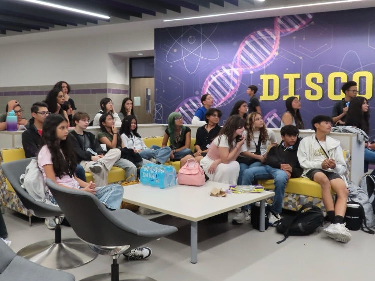A group of Pecos High School students gathered together in the CTE upstairs common area. They are seated on couches, attentively watching the presentation given by DECA officers. 