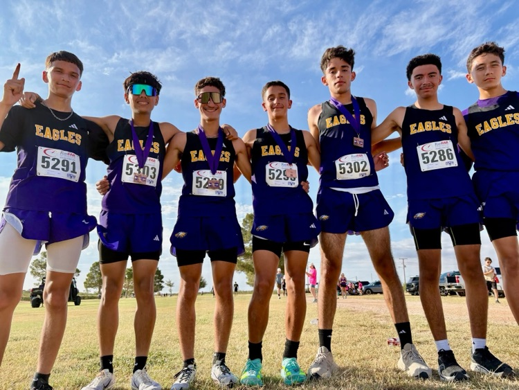 Pecos High School Eagles teamed side-hugging each other for a picture. Several runners have won medals, displayed on their neck.