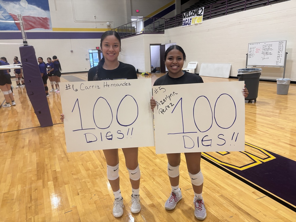 Carriz Hernandez and Azerlynn Perez holding signs that read "100 digs" and "100 digs" in gym.