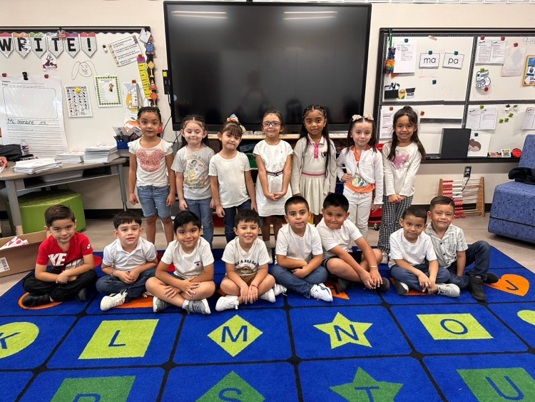 Students in front and back rows wearing white and red to show their patriotic spirit. The girls are standing in the back row, and the boys are in the front, sitting criss cross.