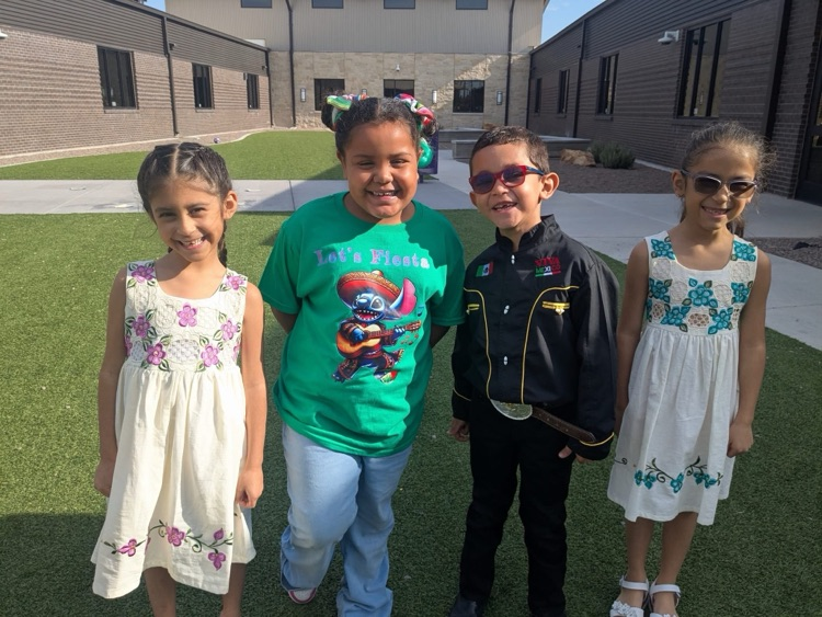 Four students lined up together wearing outfits that consists of dresses, jeans, and jackets.