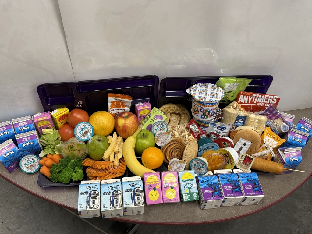 Assortment of groceries including fresh produce, packaged snacks, dairy products, and other household items arranged on a table.