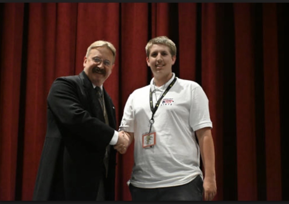 Caiden Gloor shaking the president of Boys State because his town got a award.