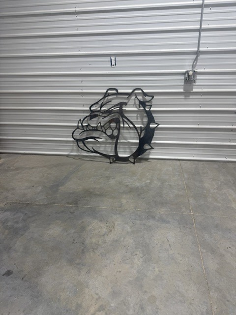Bulldog head made out of metal laying against a wall