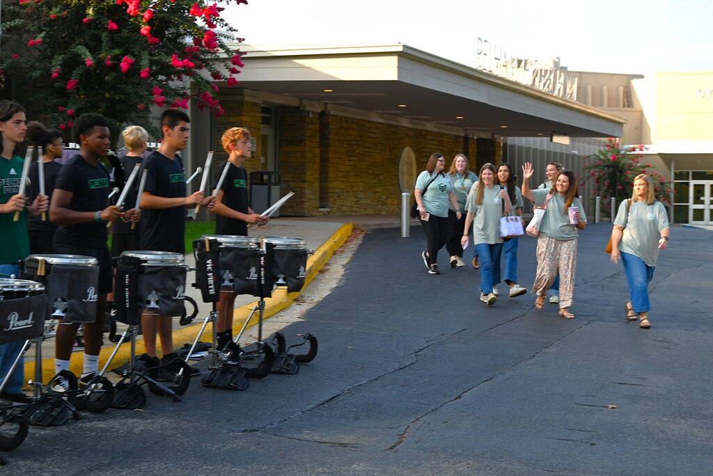 Teachers being greeted by band and walking in front of school 