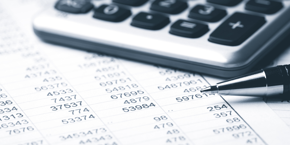calculator, pen, and spreadsheet indicating budget work