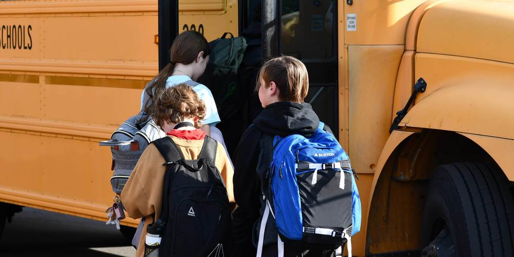 PCS SCHOOL BUS WITH CHILDREN GETTING ON THE BUS