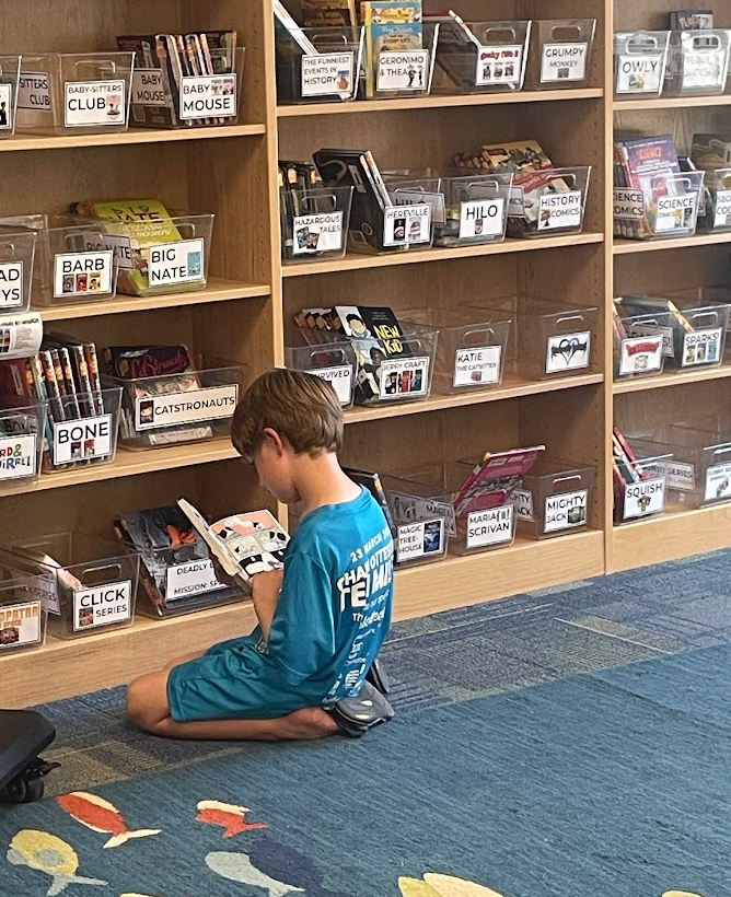 student sitting on the carpet reading a library book