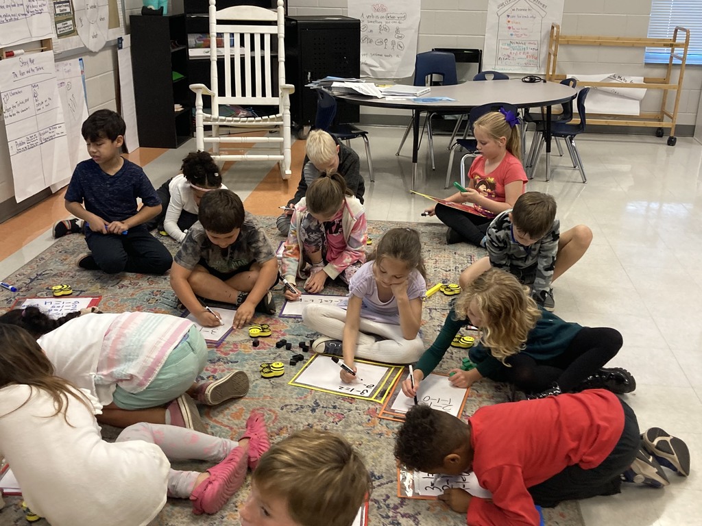 1st grade working on math problems on the carpet