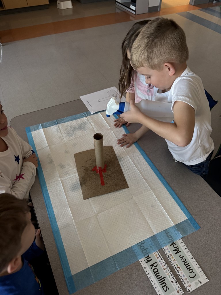 small groups of kindergarten students working at a table on a science experiment