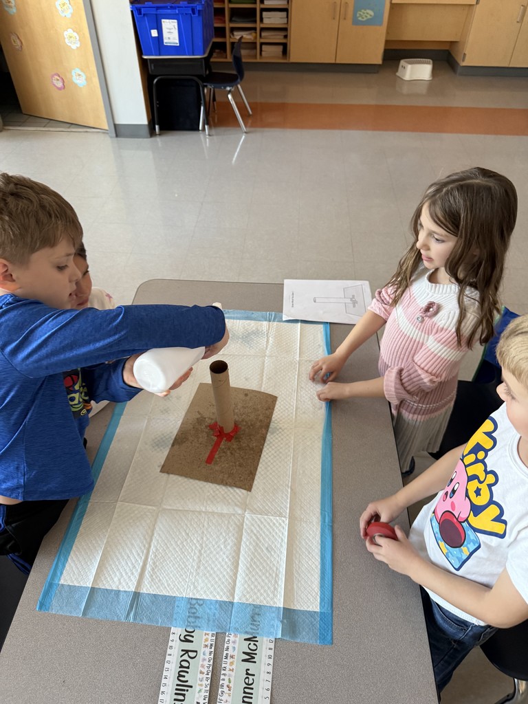 small groups of kindergarten students working at a table on a science experiment