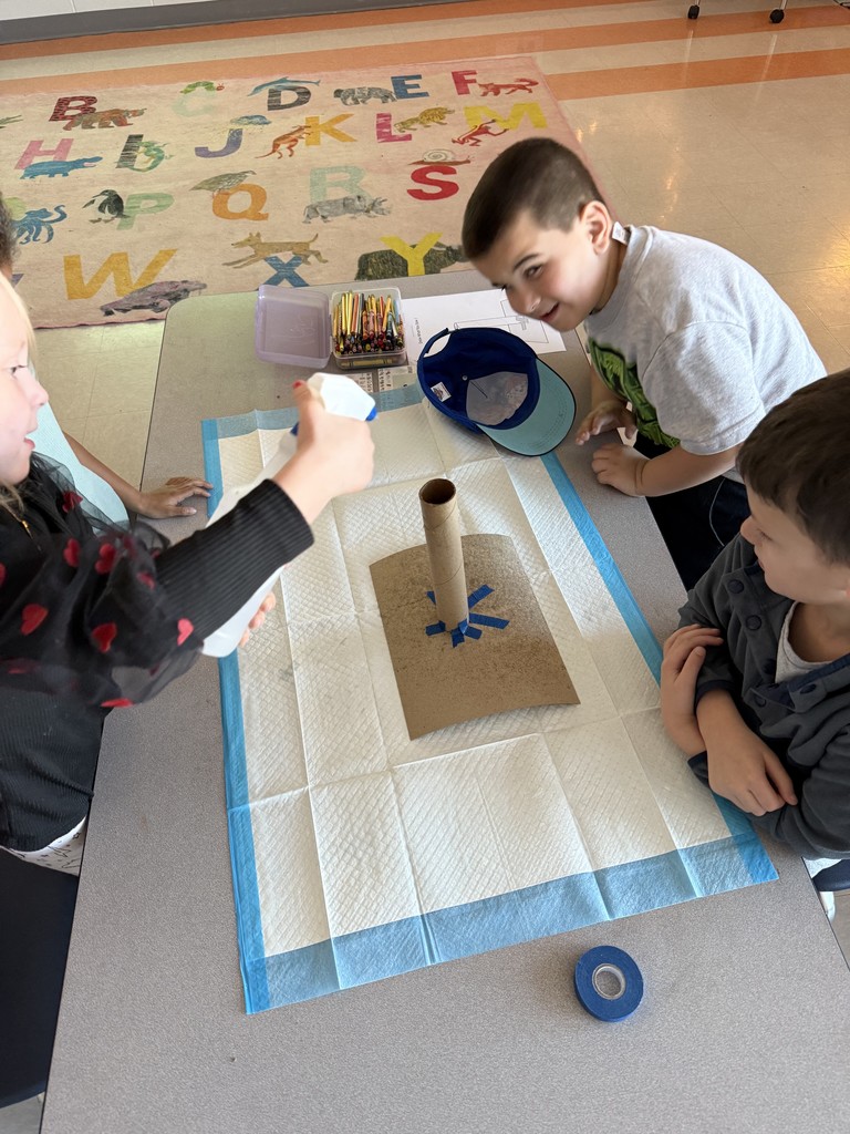small groups of kindergarten students working at a table on a science experiment