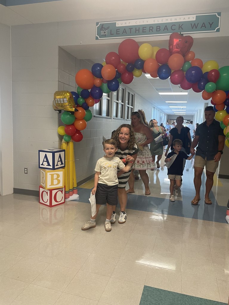 student and parent walking through kindergarten balloon arch 