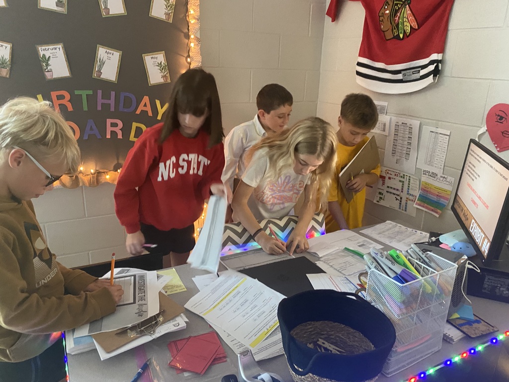 5th graders looking around a teachers desk