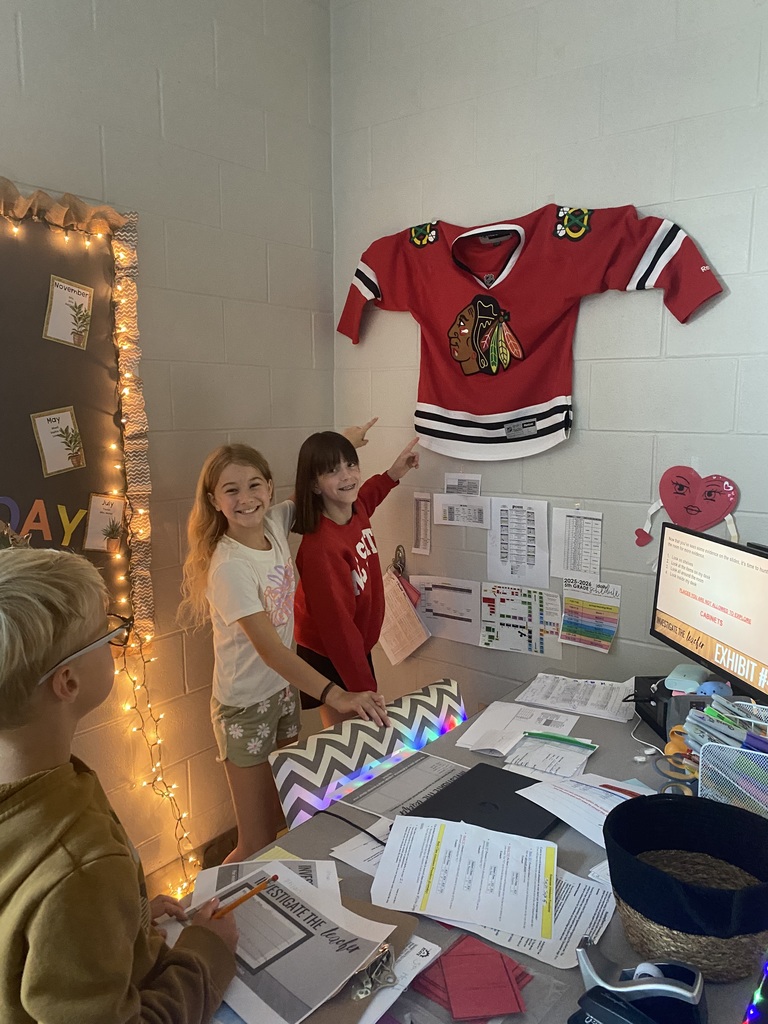 5th graders looking around a teachers desk