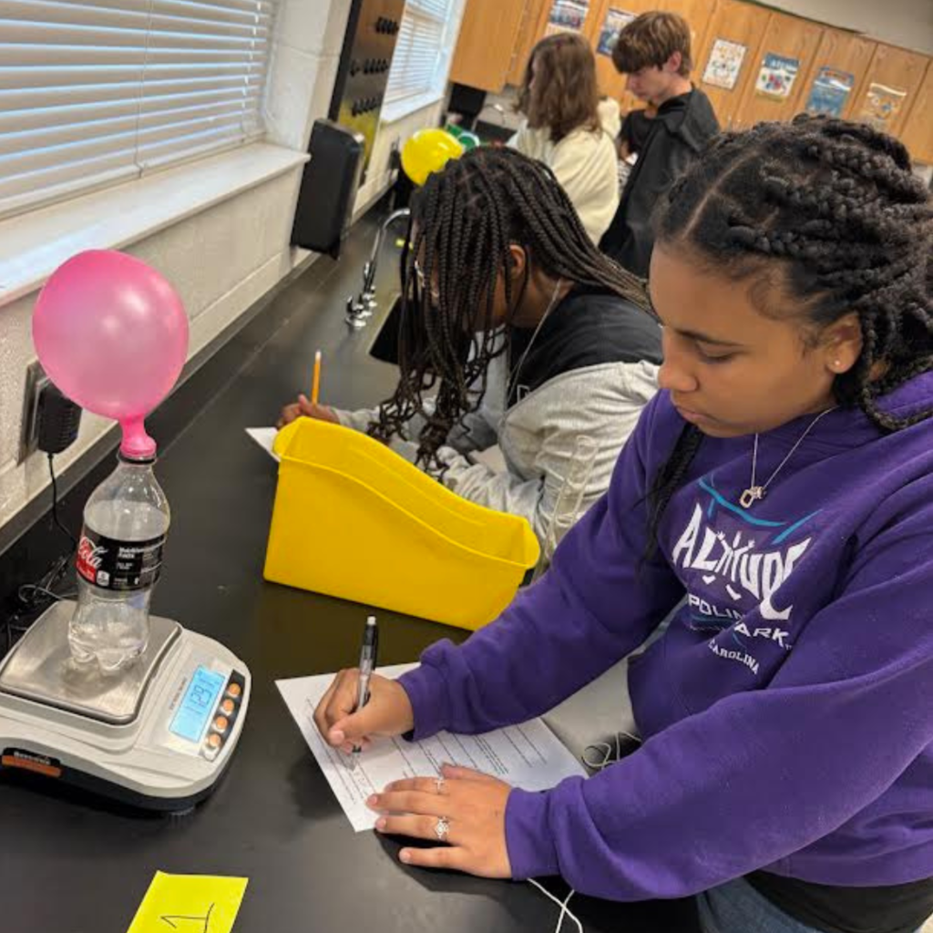 student writing on paper for science lab