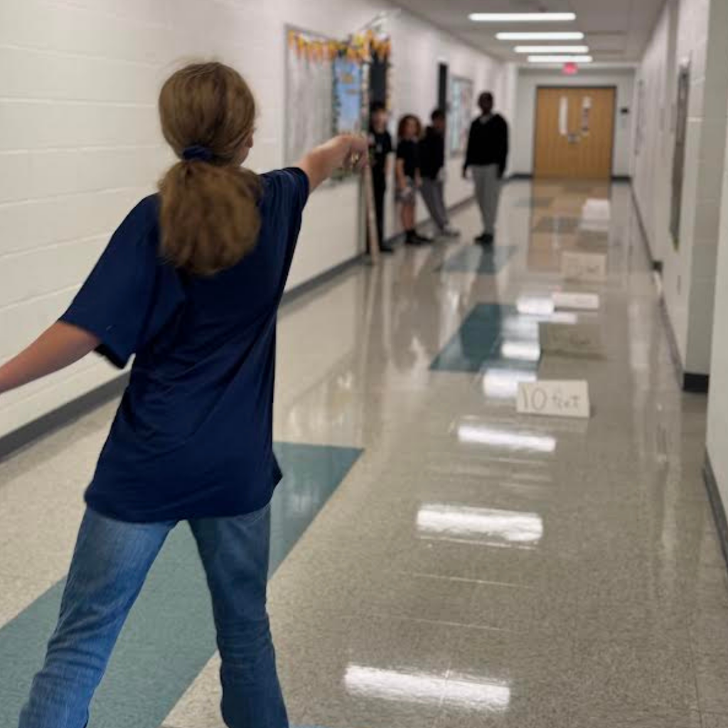 students testing paper airplanes in hallway