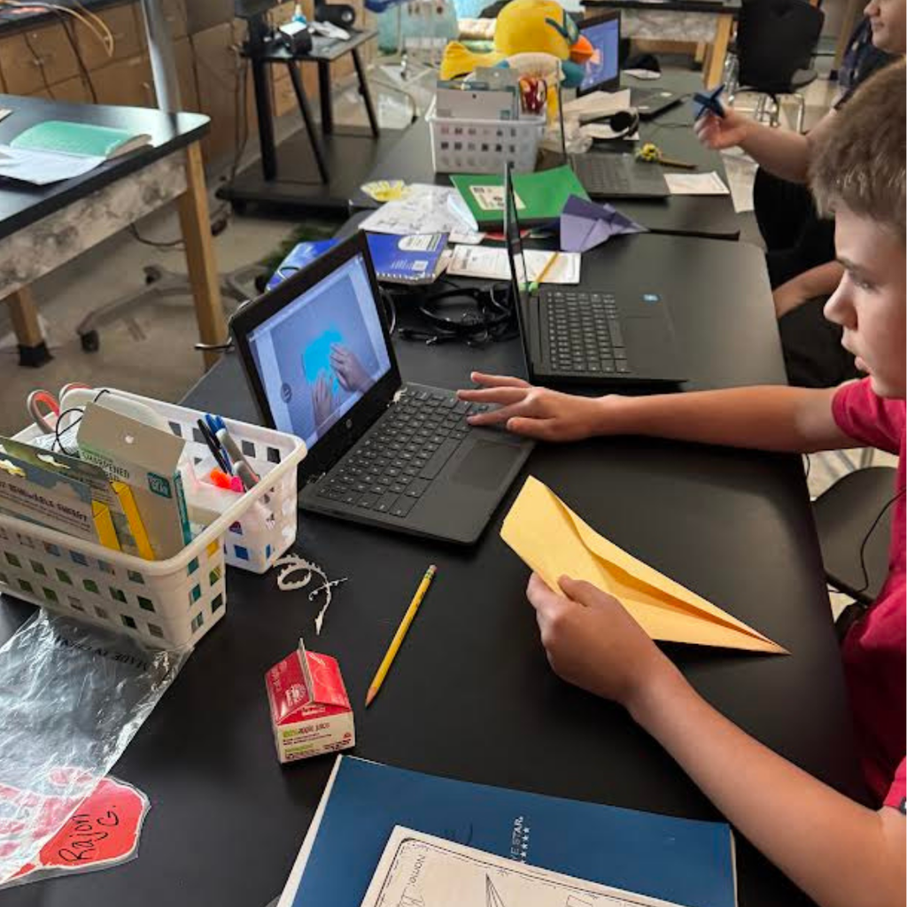 students making paper airplanes in classroom