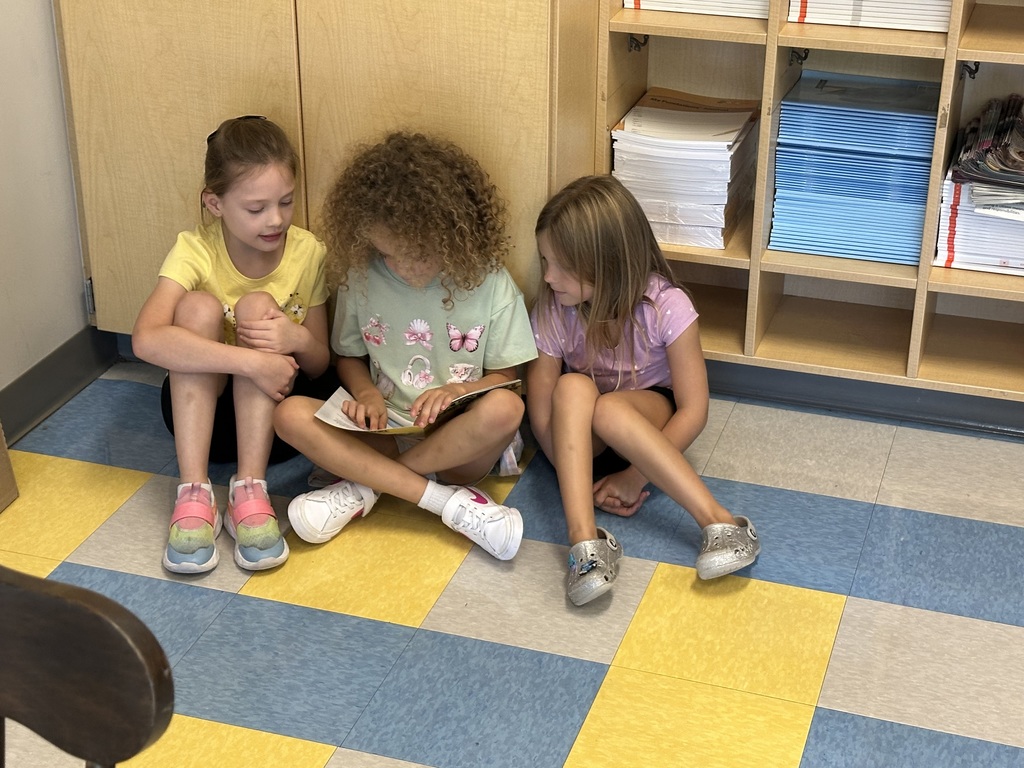 1st graders looking at a book in a small group