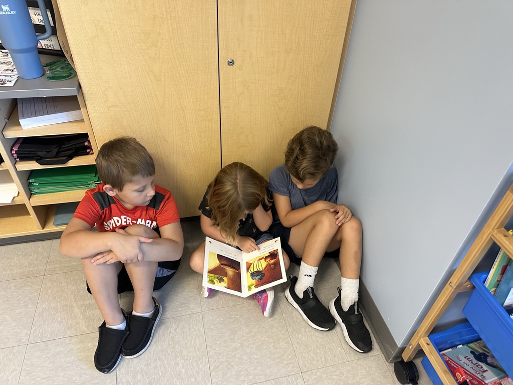 1st graders looking at a book in a small group
