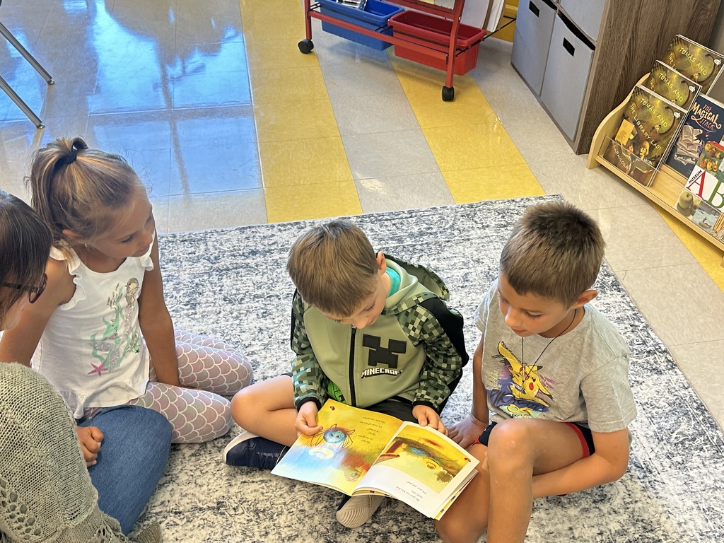 1st graders looking at a book in a small group