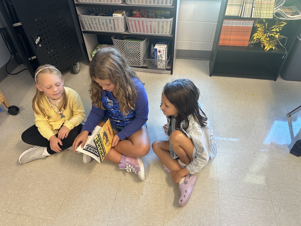1st graders looking at a book in a small group