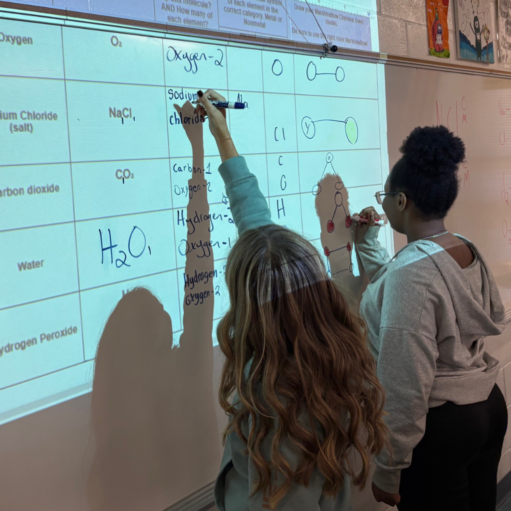 students writing on board in classroom