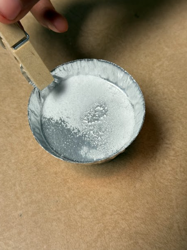 foil tray with alum held over fire to observe changes