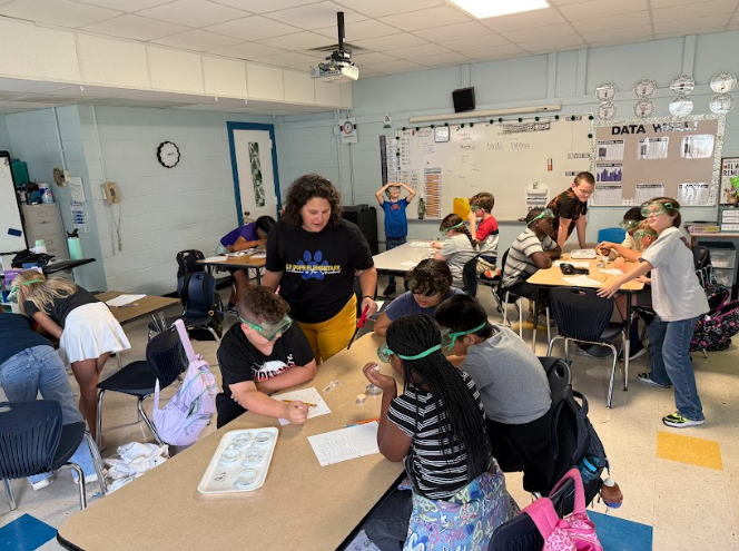 students and teacher completing science lab