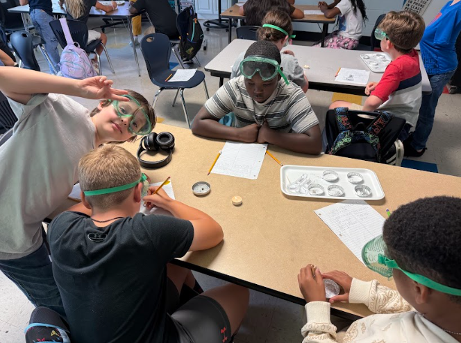 students and teacher completing science lab