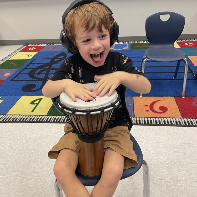 kindergarten student playing a drum in music class