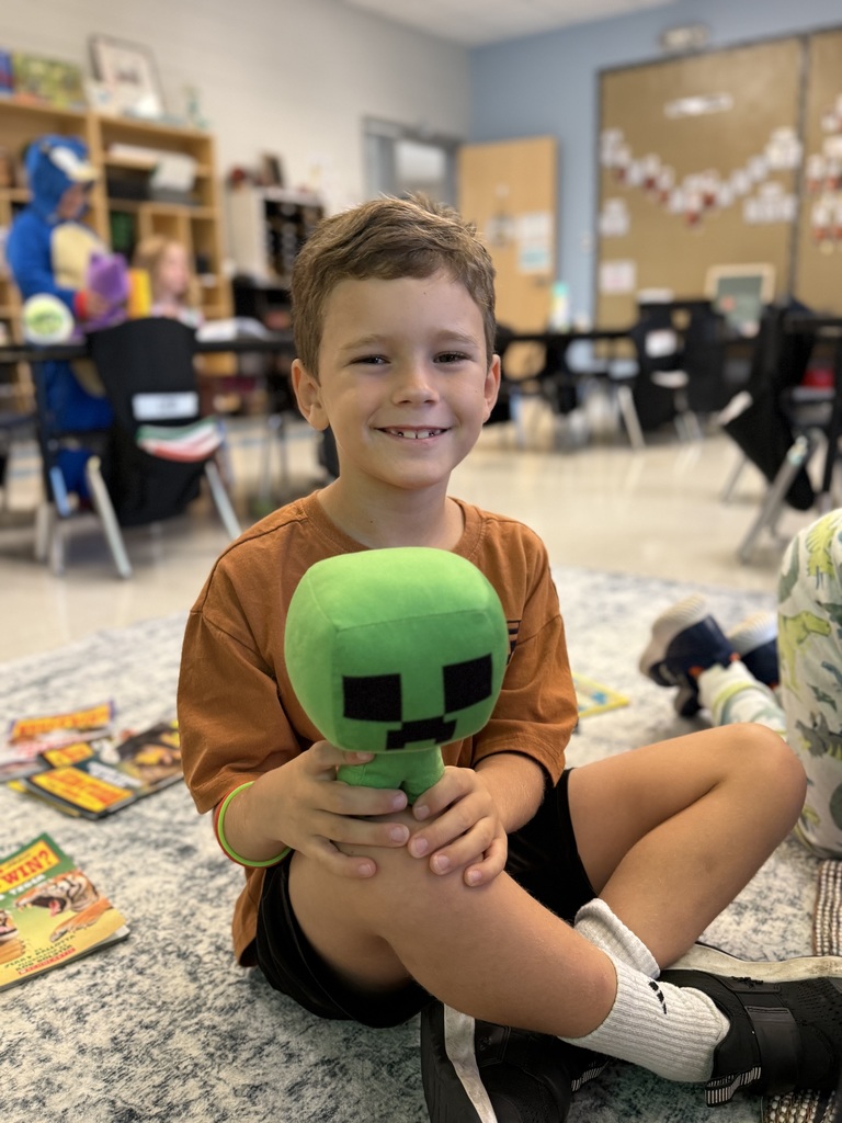 first grader working on the carpet and holding a stuffed animal