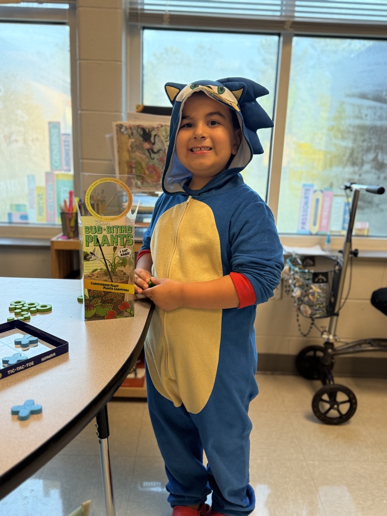 first grader working at their desk and holding a stuffed animal