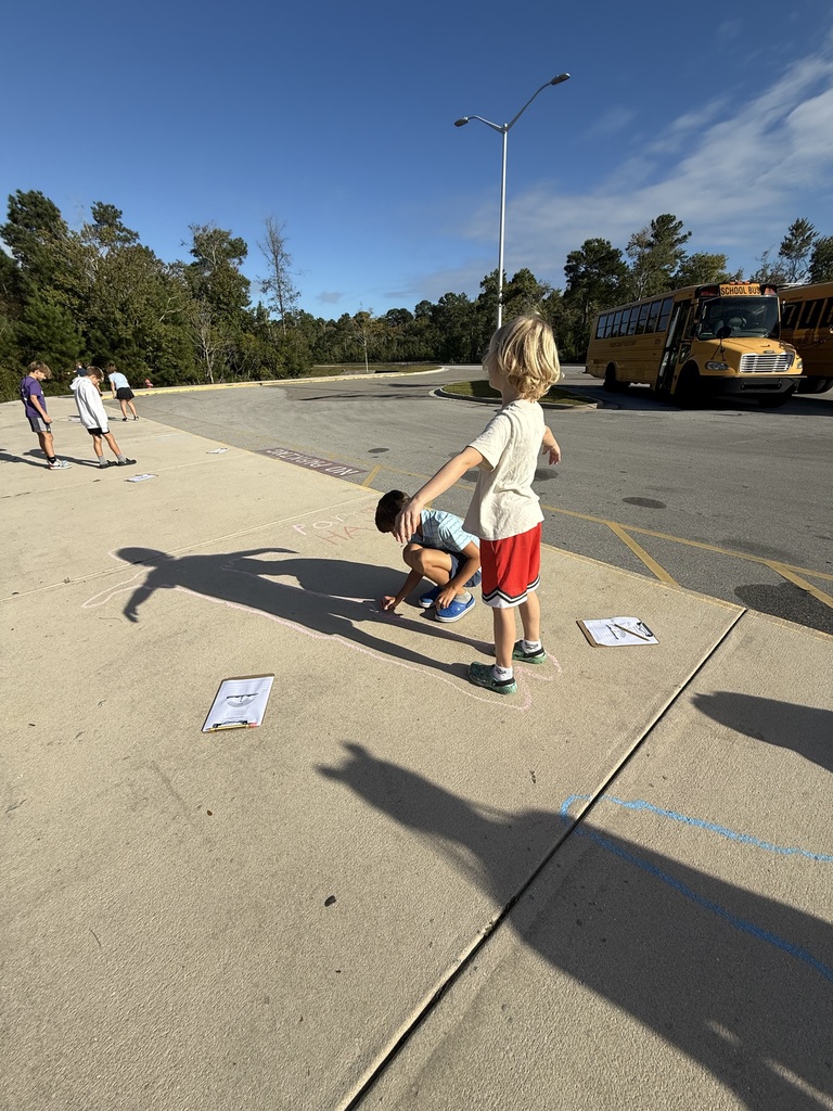 student tracing their shadows outside