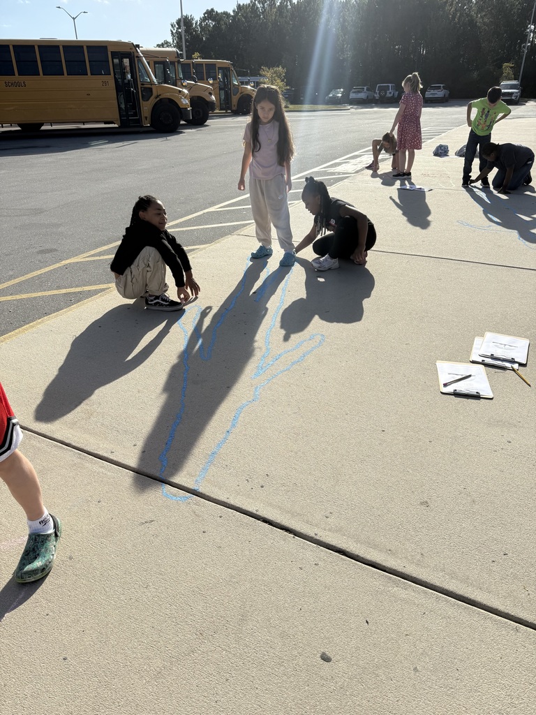 student tracing their shadows outside