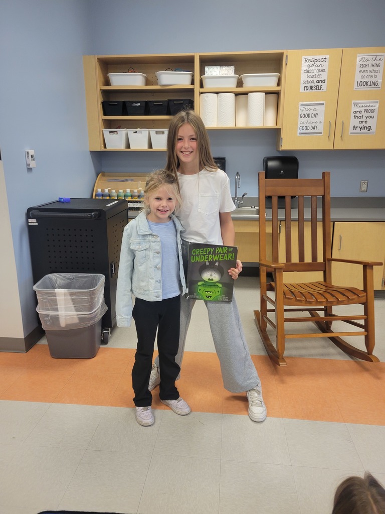 sisters standing next to each other holding a book