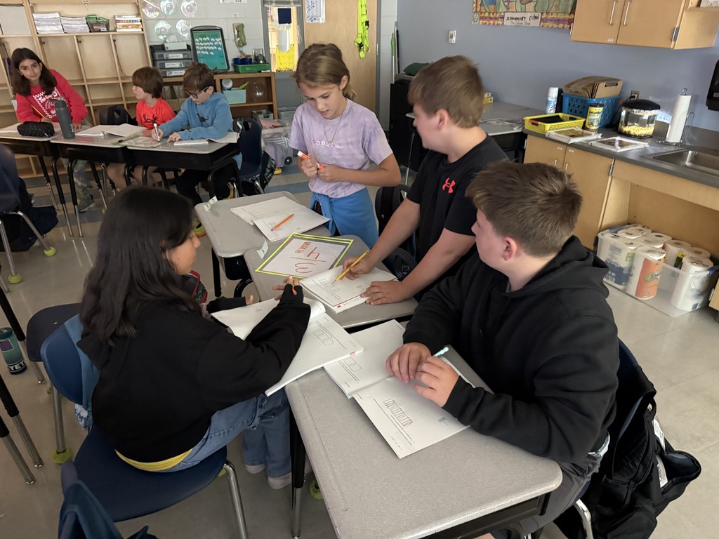 5th graders working in small groups on math problems at their desks