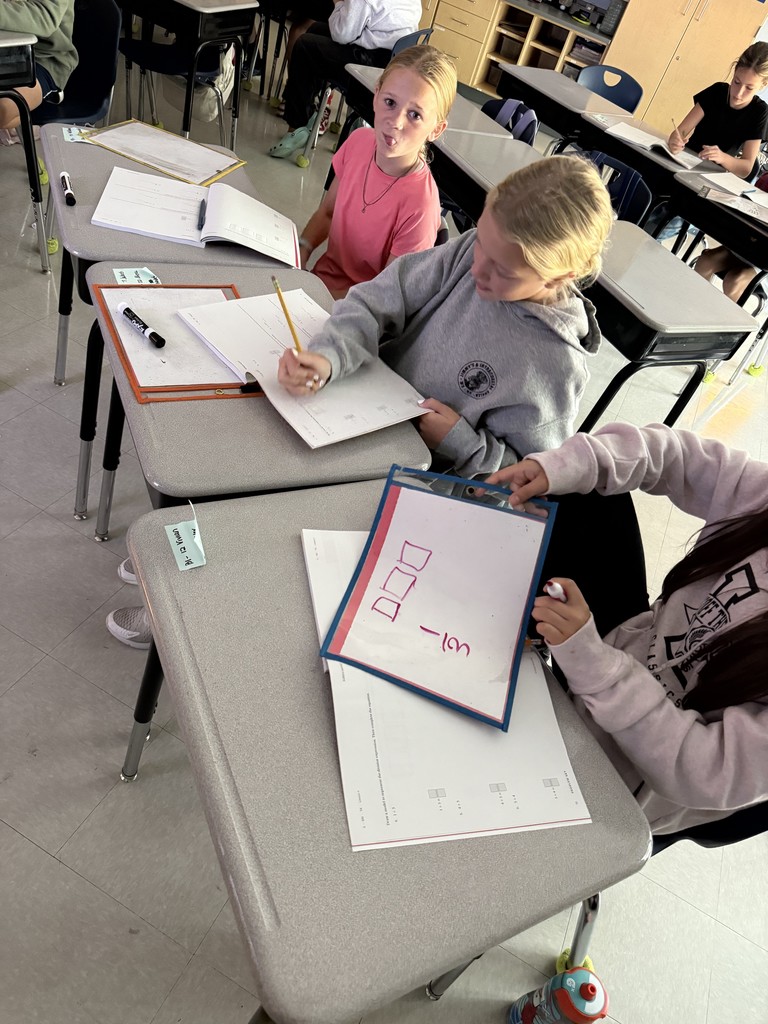 5th graders working in small groups on math problems at their desks